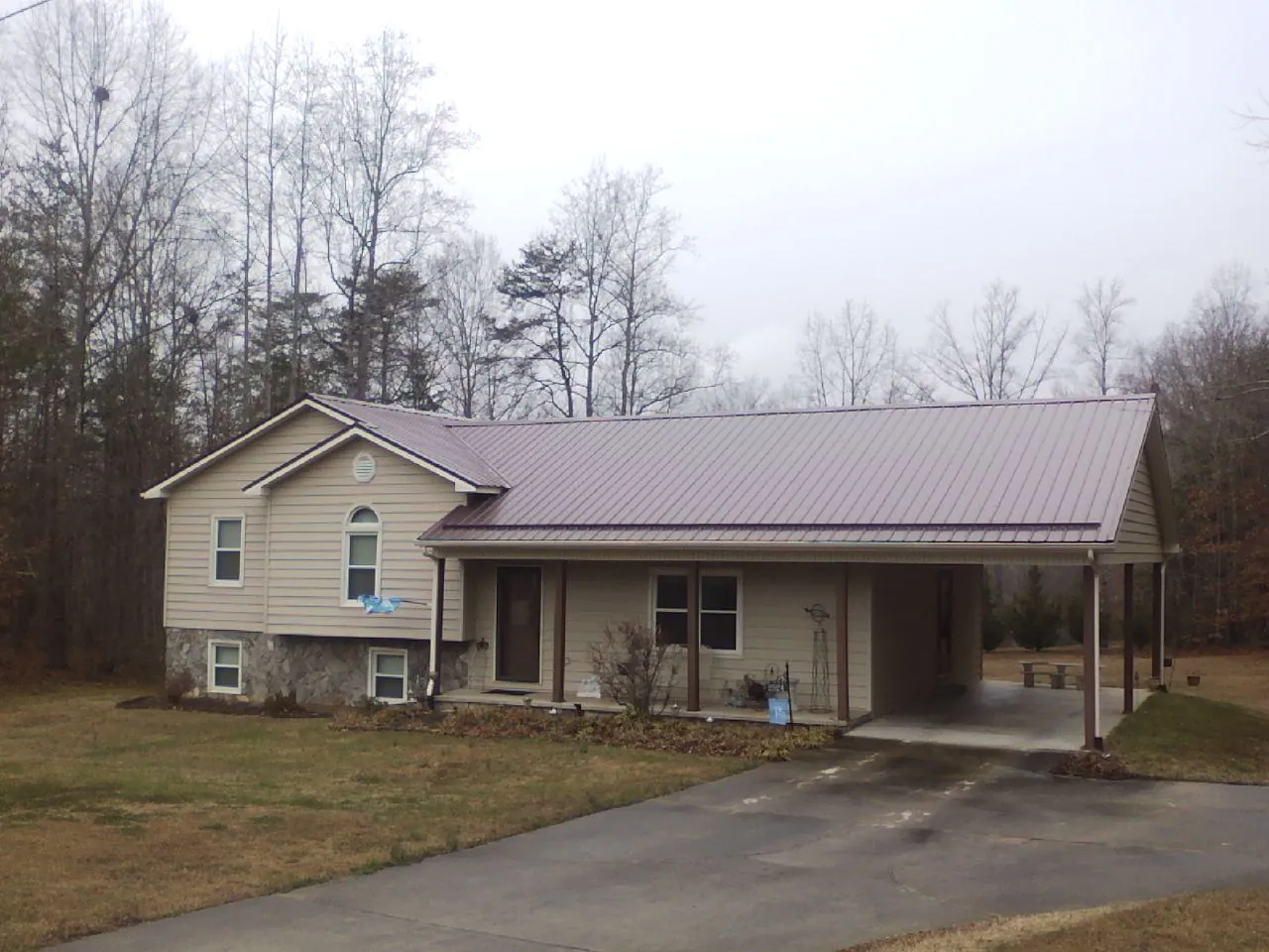 Burgundy metal roof on a tan split level home with an attached carport in Conway Springs