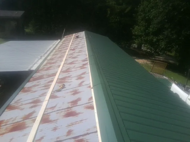 Old rusted panels beside newly installed green metal roofing — Wind Damage Roof Repair by Roofing Brothers in Conway Springs