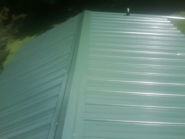 New green metal panels meeting at the ridge of a roof — Flat Roof Repair work by our crew in Conway Springs