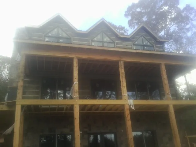Dormers and porch framing on a large log home under construction — Roof Coating work by our crew in Conway Springs