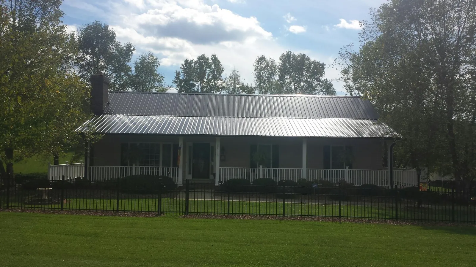 Gray metal roof on a brick ranch with a full width front porch — Gutter Guard Installation work by our crew in Conway Springs