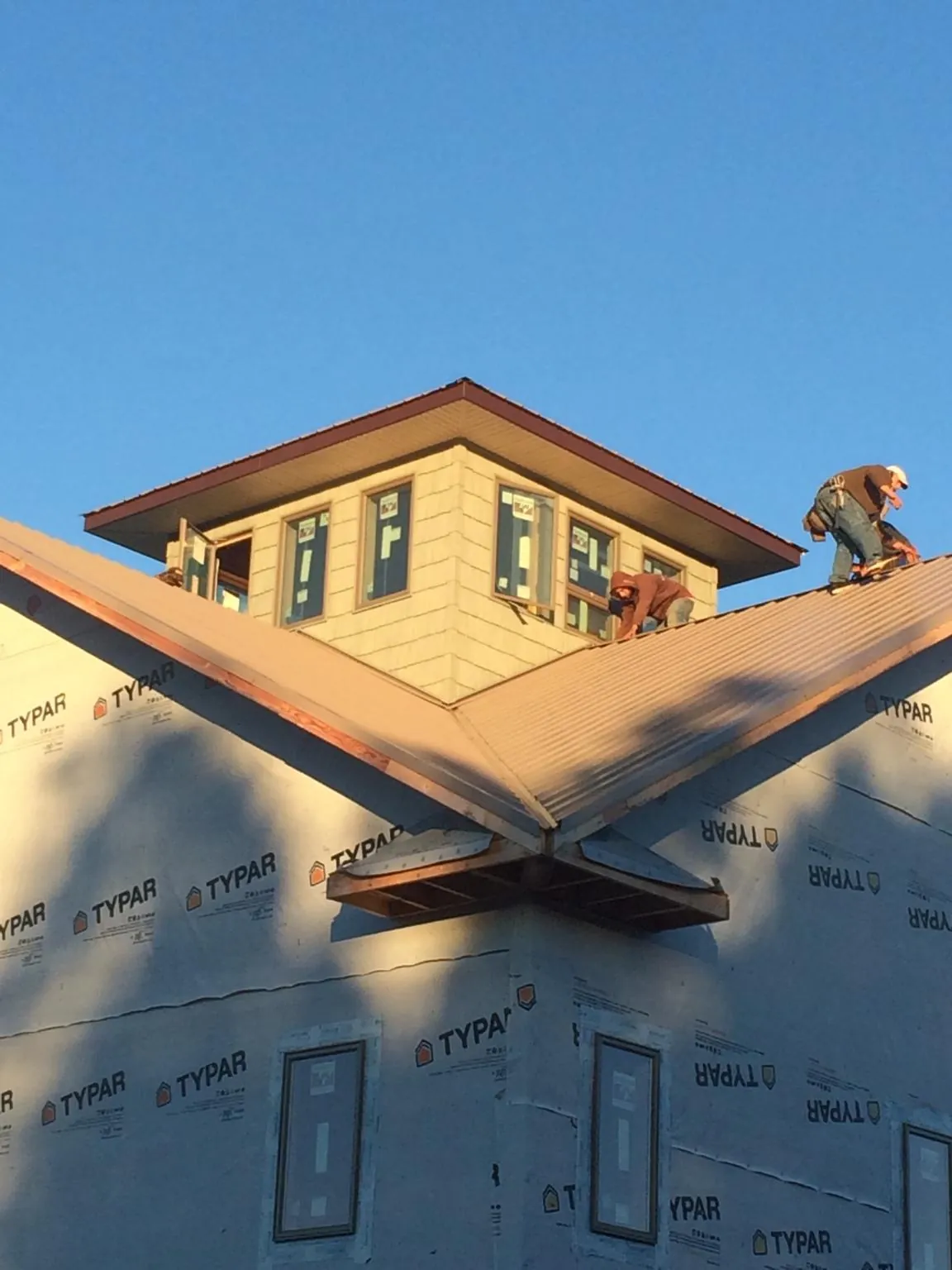 Roofers working around a rooftop cupola on a new metal roof at sunset — Roof Waterproofing in Conway Springs by Roofing Brothers